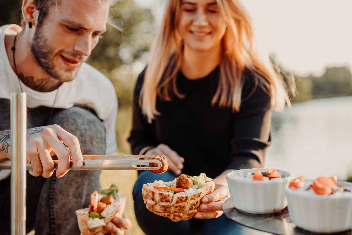 BBQ-Tool-Set Auf dem Bild sind ein Mann und eine Frau zu sehen, die Essen an einem Picknicktisch essen.