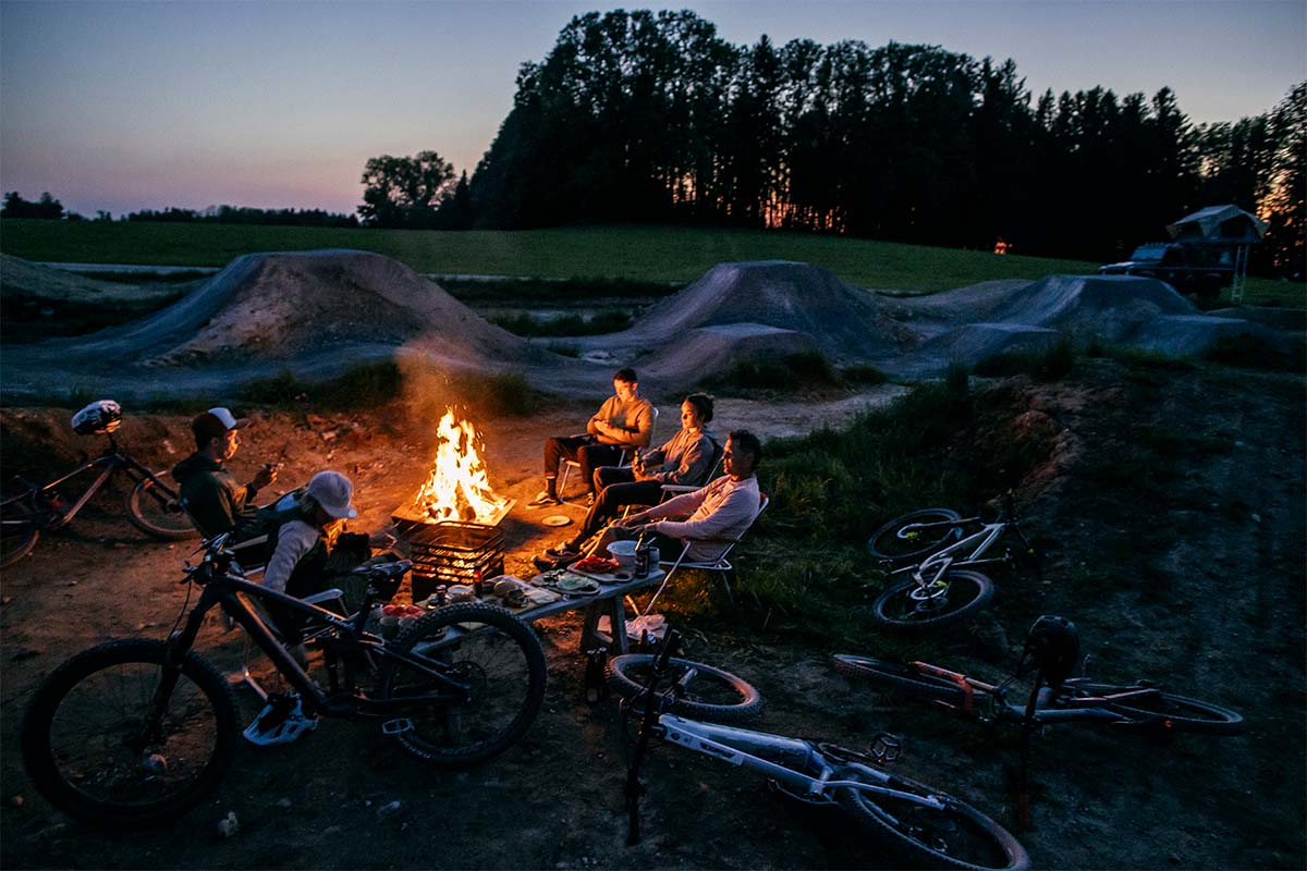 TRIPLE 90 Bol à Feu Un groupe de personnes assis autour d'un feu, la cheminée TRIPLE 90 complète le moment avec son design réfléchi.
