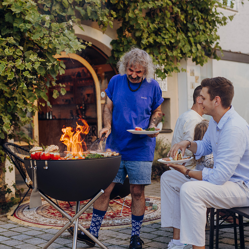 A man and a woman sitting around a fire pit, enriched by the presence of the Bowl 57