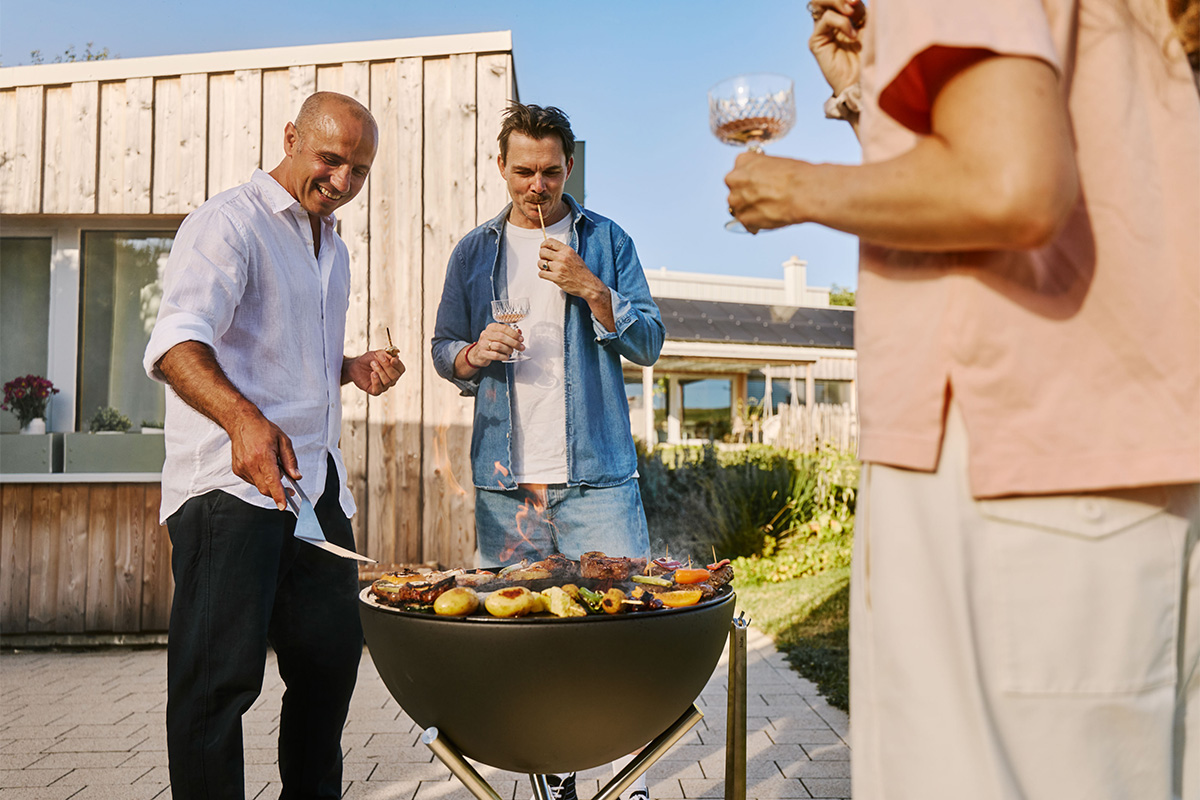 BOWL 57 Set Plancha Grille basse Le bol 00256 Plancha 57 s'intègre parfaitement dans le cadre, où une personne cuisine de la viande sur un grill.