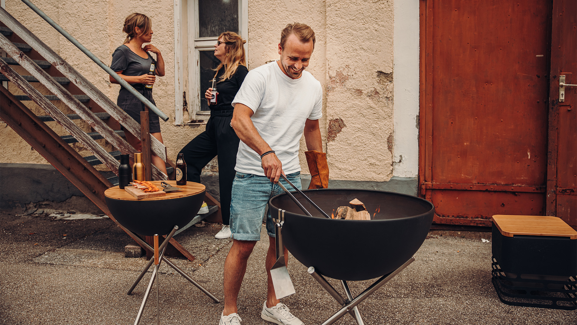 Sur cette image, un homme et une femme se tiennent près d'un barbecue, avec des pinces.