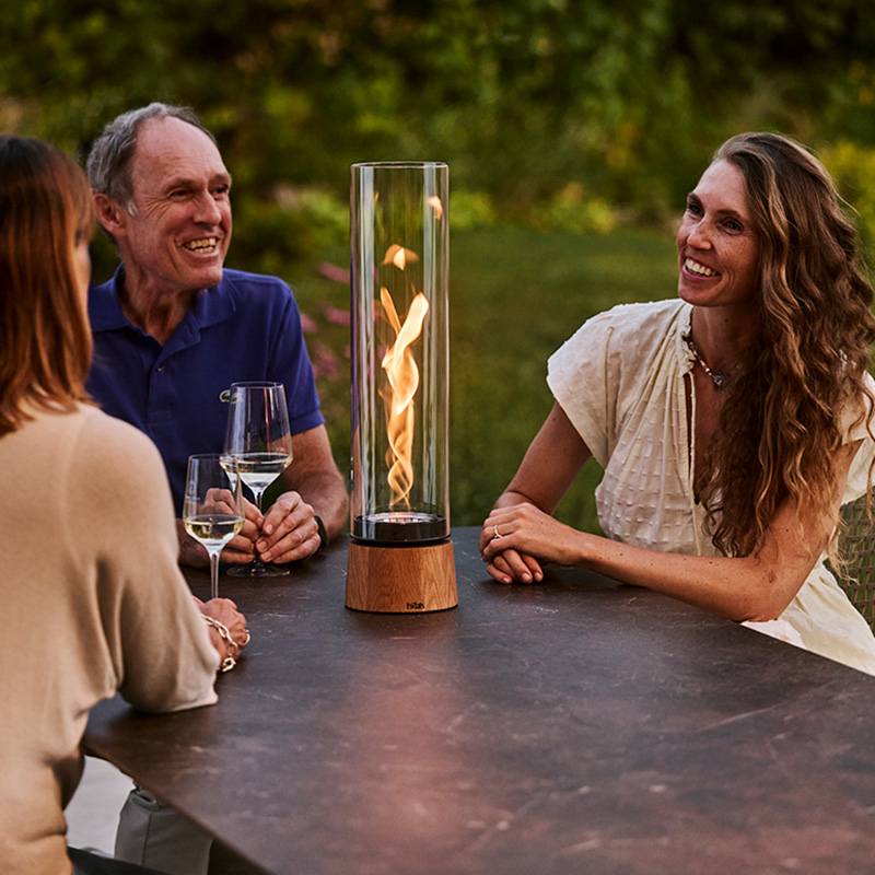 Drei Personen sitzen an Gartentisch mit SPIN air in der Mitte und unterhalten sich.