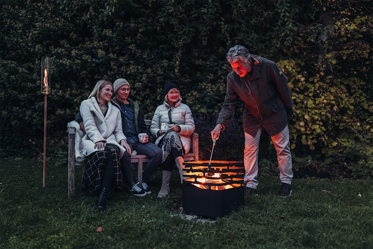 Tisonnier avec souffleur de flamme sur pied en inox Découvrez un groupe de personnes assises autour d'un feu de camp avec la touche raffinée du 00581 Poke-soufflet.