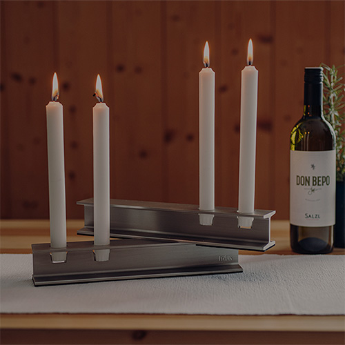 Une bouteille de vin et des bougies sur une table, montrant des exemples de personnalisation de produit avec le bougeoir en métal Henry.