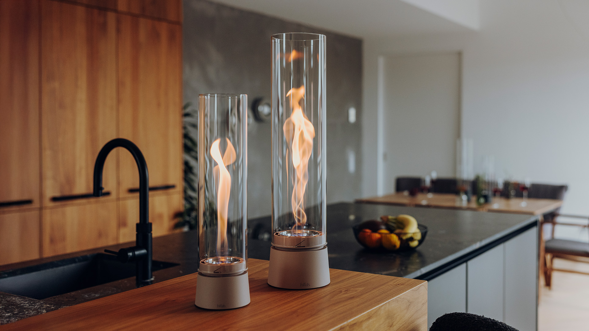 SPIN air 900 und SPIN air 1200 stehen auf einer Kücheninsel. Im Fokus steht die Flamme der Tischfeuer.