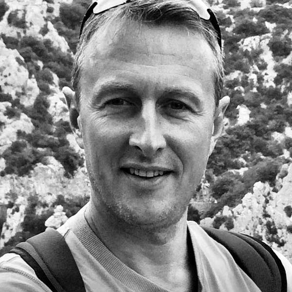 Un homme avec un sac à dos sourit à l'appareil photo