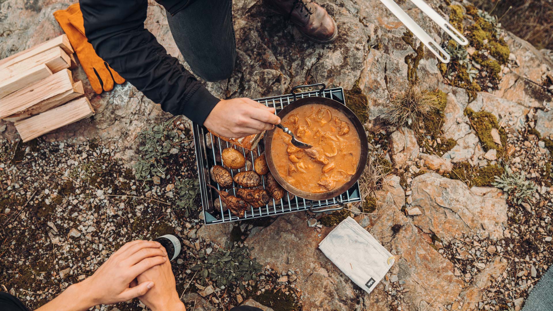 Das Foto zeigt eine Person, die Essen auf einem Grill zubereitet, mit dem CRATE Grillrost.