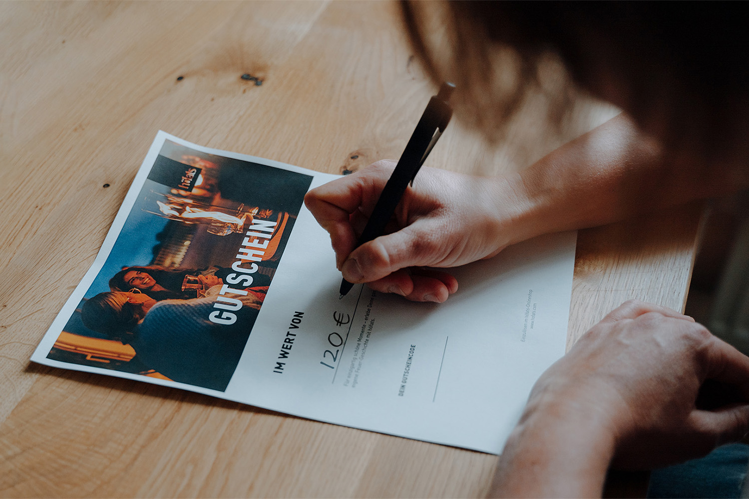 BONS CADEAUX ÉLECTRONIQUES Une image montrant une personne écrivant sur un morceau de papier, avec le BON CADEAU numérique.