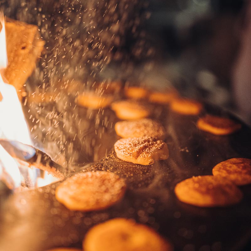 Depicted here is a person is cooking food on a grill, with the BOWL Fire Bowl.