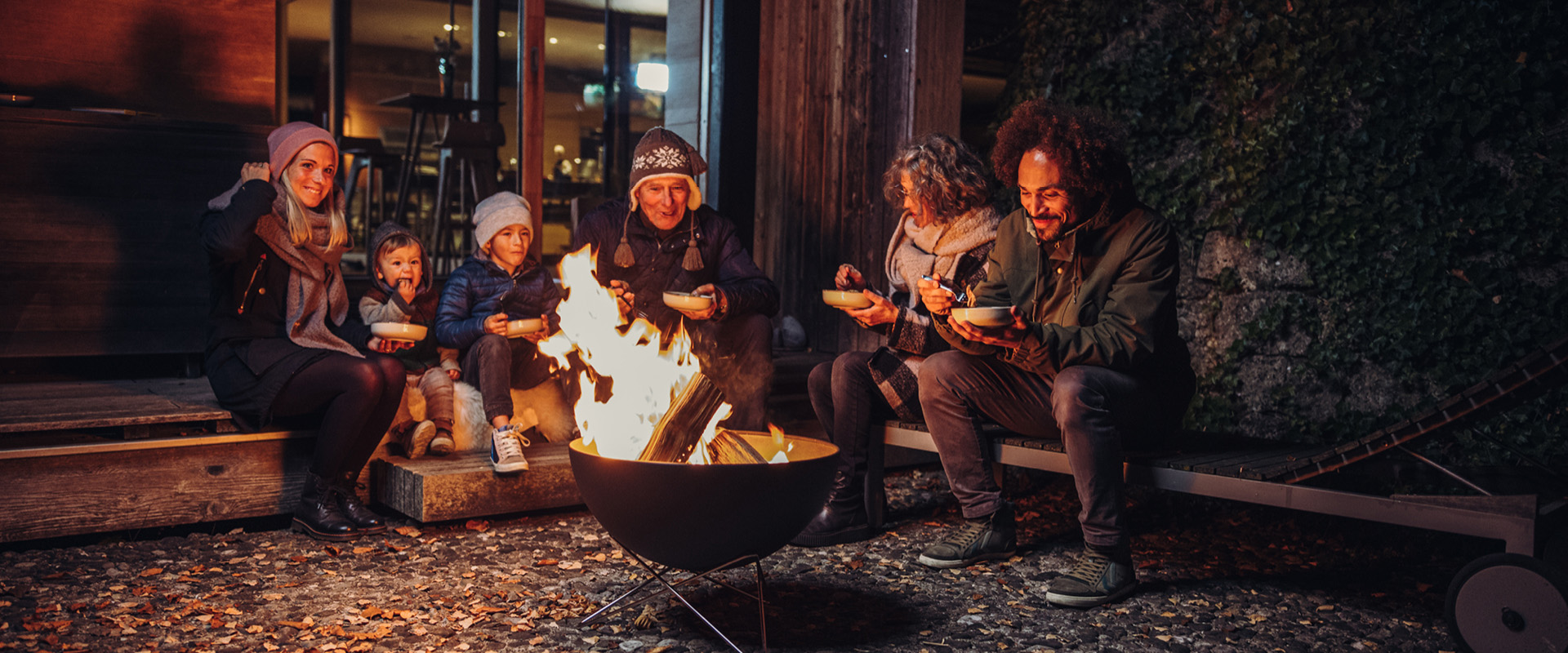 Das Foto zeigt eine Gruppe von Menschen, die um ein Feuer sitzen, mit dem FIRE KITCHEN Ersatzregalboden in Schwarz.