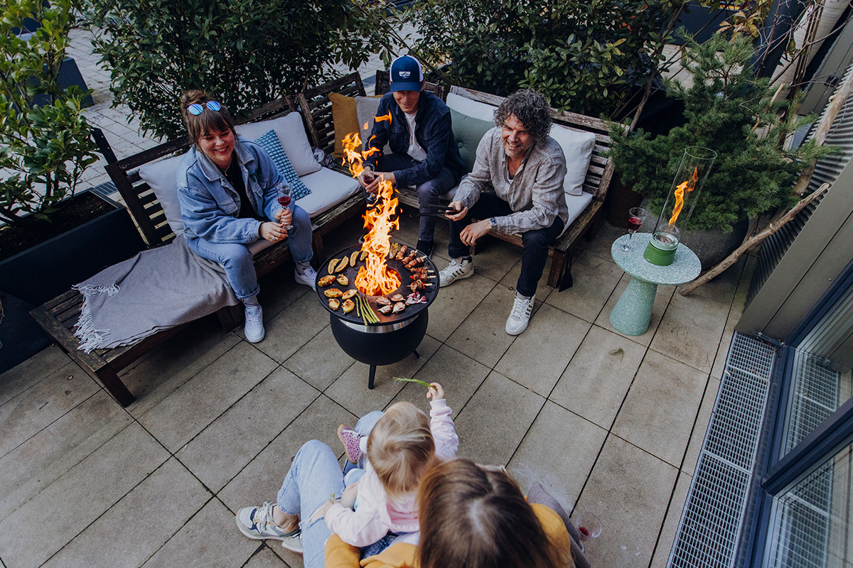 MOON 45 Plancha Une représentation d'un groupe de personnes assises autour d'un feu de camp, mettant en vedette la cheminée 00861 MOON 45 Plancha comme élément central et utile.