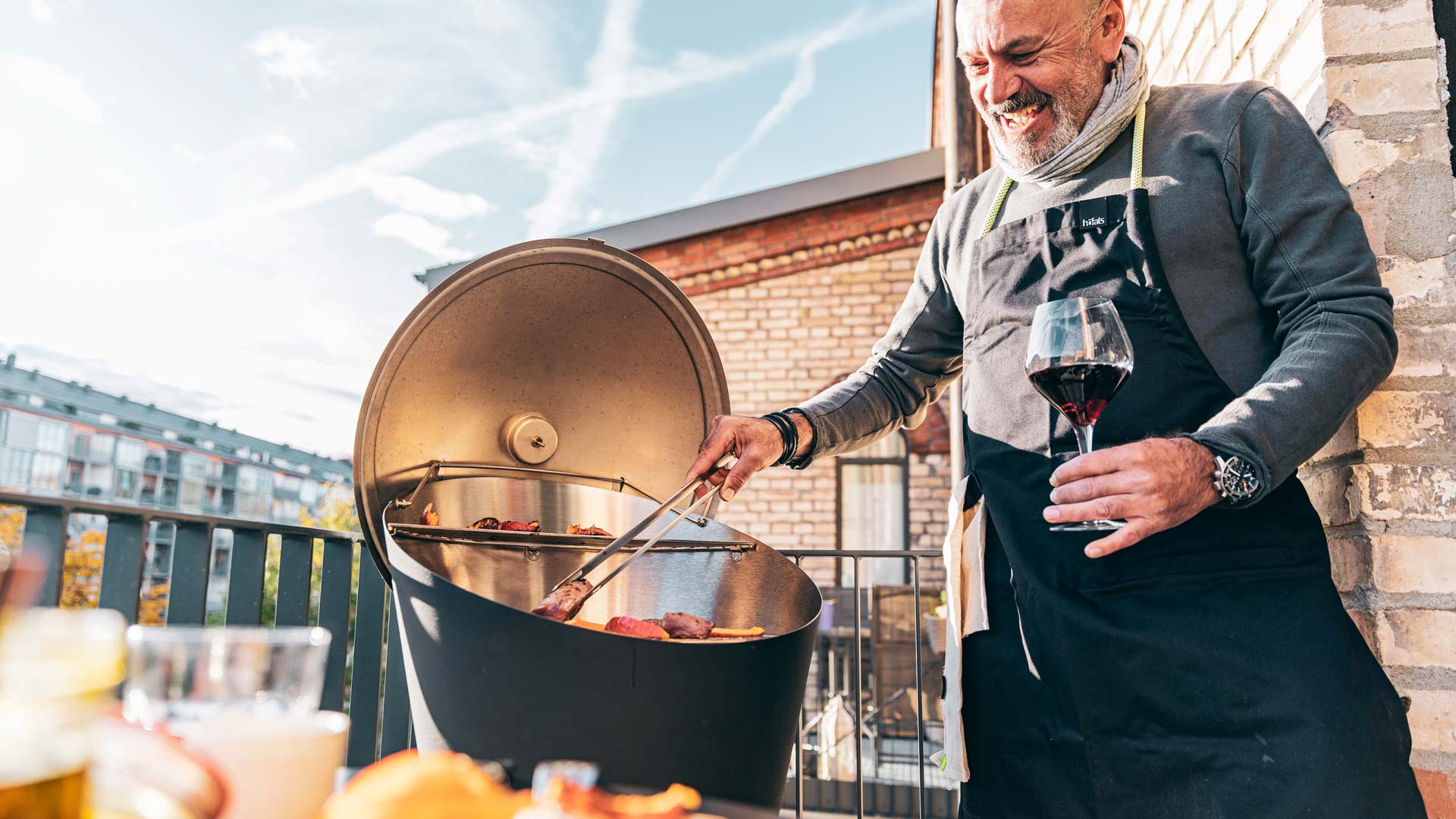 Vue d'un homme en train de cuisiner de la nourriture sur un grill à l'extérieur, avec le couvercle CONE.