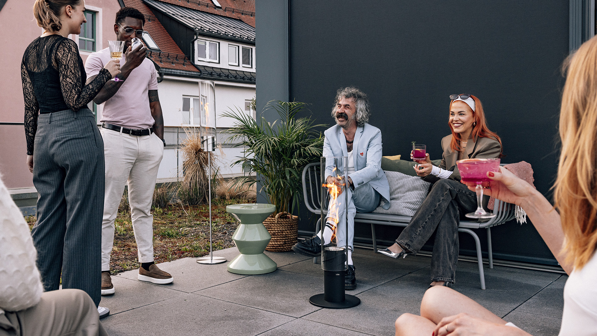 Das 00630 Spin 1500 Standerhöhung Black wird als Gruppe von Menschen gezeigt, die auf einer Terrasse sitzen, was ein stilvolles und zugängliches Bild vermittelt.