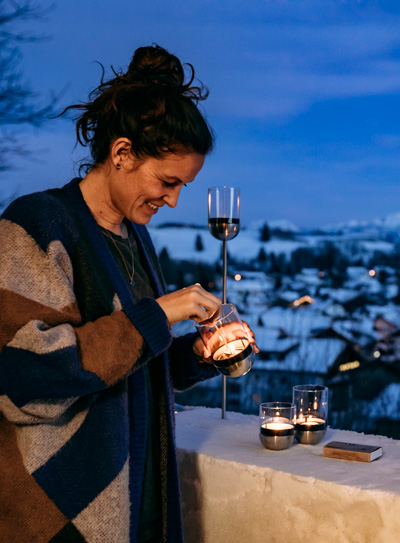 Illustrated is a woman is holding a wine glass, with the LOGO GRAVITY CANDLE M90 Lantern.