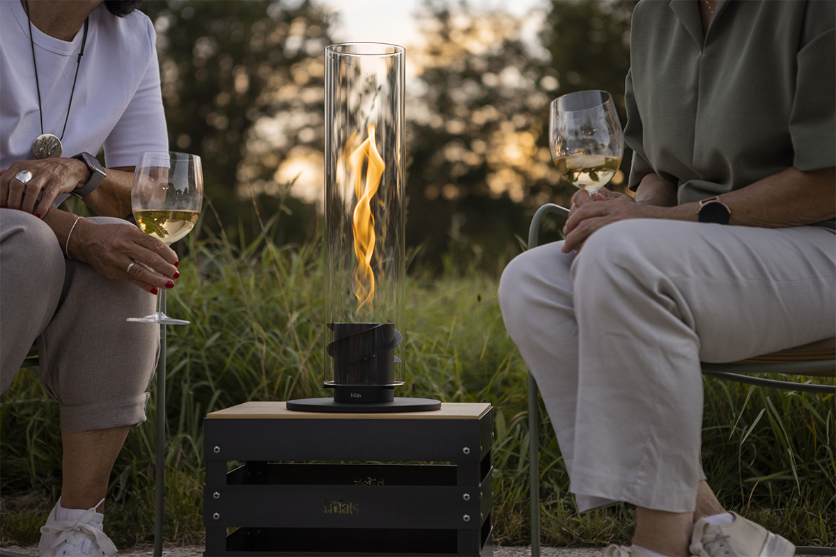 SPIN 900 Tabletop Fireplace black An inviting scene with a man and woman sitting on a bench with wine glasses, highlighted by the presence of the 00700 Spin 1200 Tablefire black
