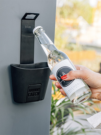 Une personne ouvre une bouteille d'eau d'une glacière, avec le Johnny Catch Cup décapsuleur ajoutant une touche fonctionnelle et élégante à la scène.
