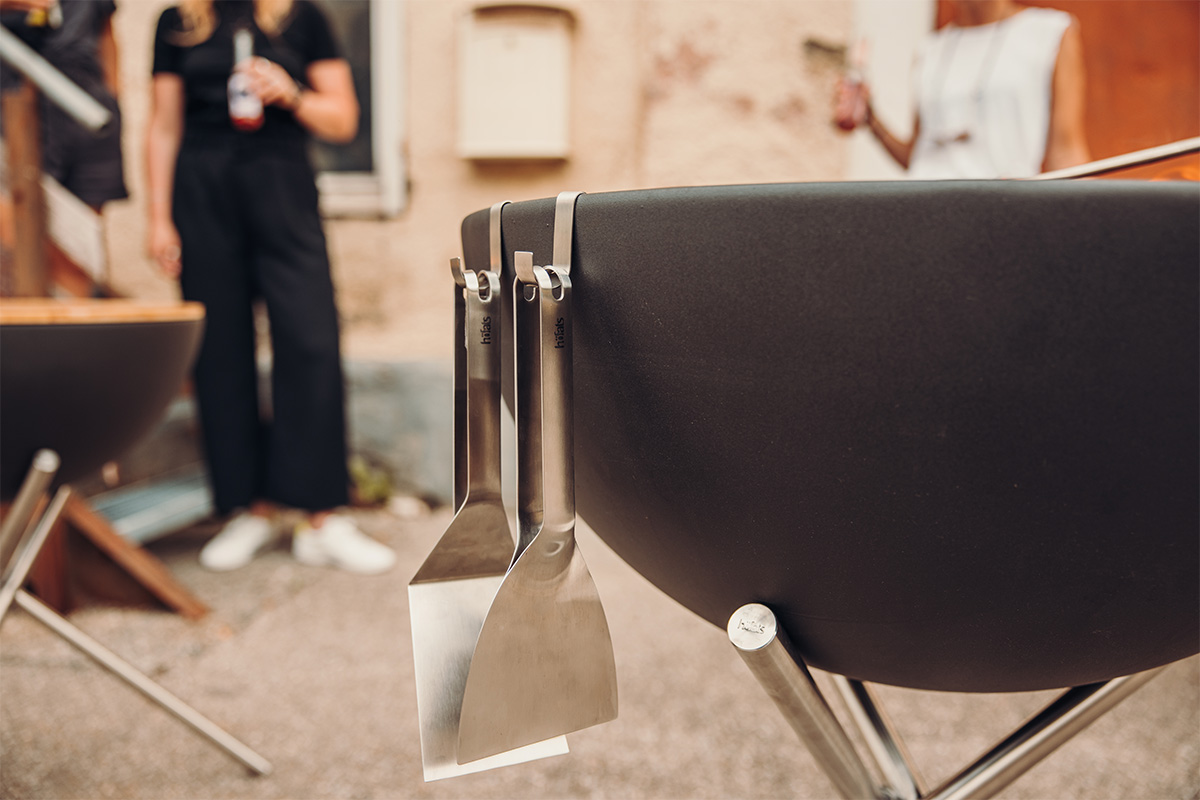 Une scène accueillante avec un brasero BOWL, mise en valeur par la présence de l'ensemble d'outils de grillage, montrant les différents outils suspendus au bol.