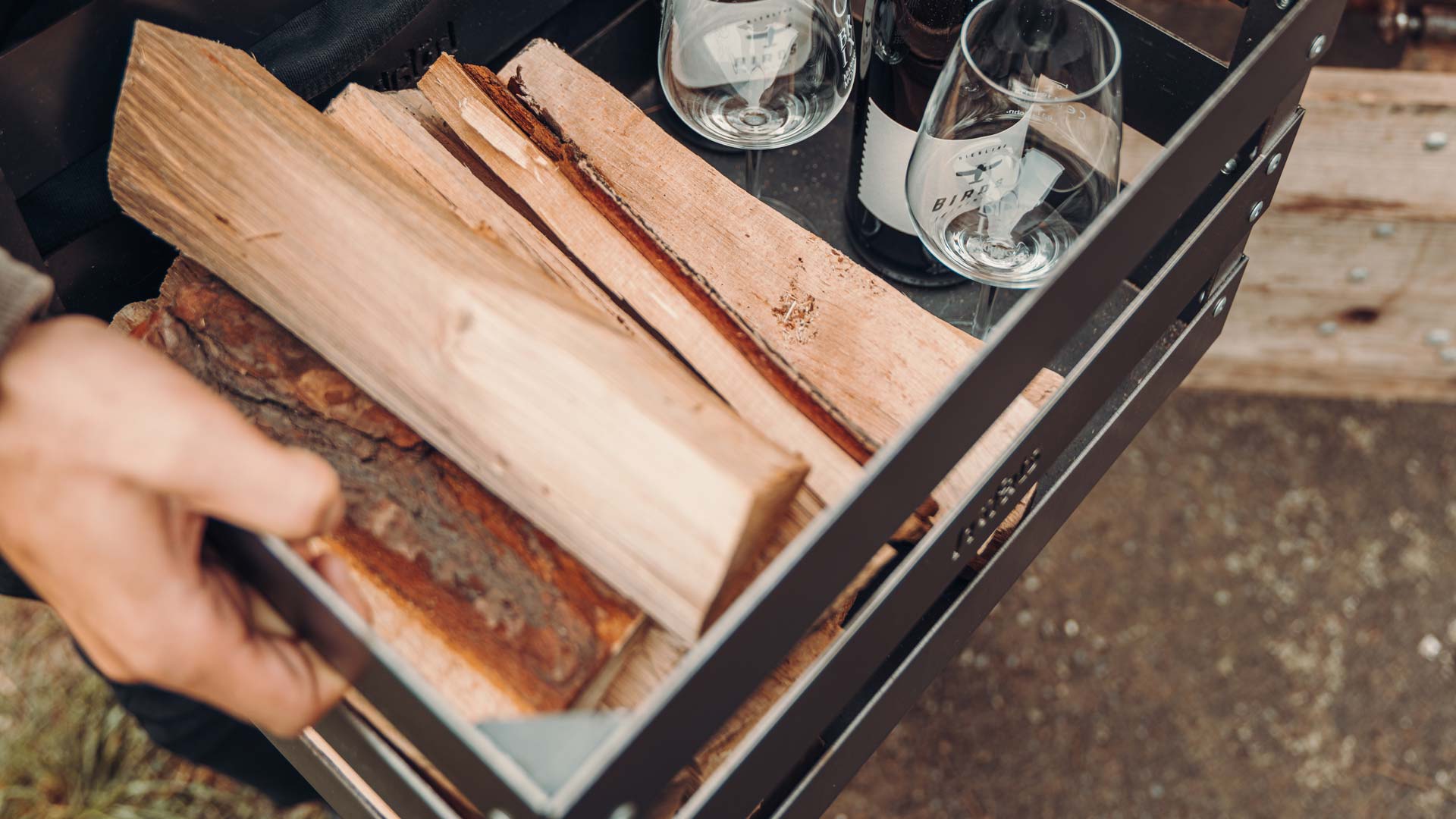 On voit ici une personne tenant un plateau de bois, avec le bois de chauffage Premium.