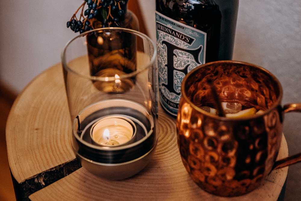 A view of a candle and a glass of wine on a table, with the LOGO GRAVITY CANDLE M90 Lantern.