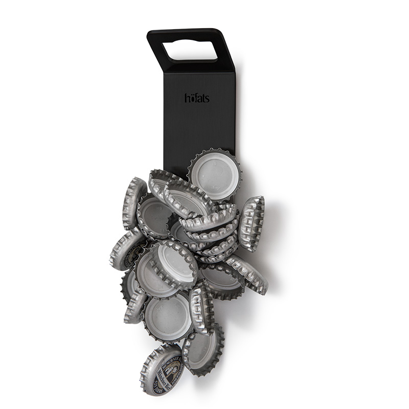 Le 00841 Johnny Catch Magnet Black Décapsuleur est présenté comme un décapsuleur avec des capsules de bouteilles qui y adhèrent, créant une image élégante et accessible.