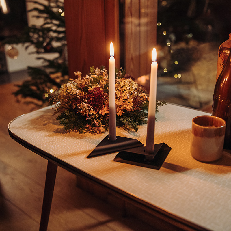 Scene showing a candle and a vase on a table, where the Square Candle Candleholder stands out for its practical elegance.