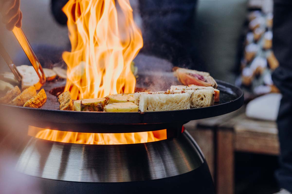 MOON 45 Set Plancha Grille bas Griller devient une expérience avec l'ensemble Moon 45 Plancha BBQ bas, comme le montre la scène d'un plat en cours de préparation à l'extérieur.