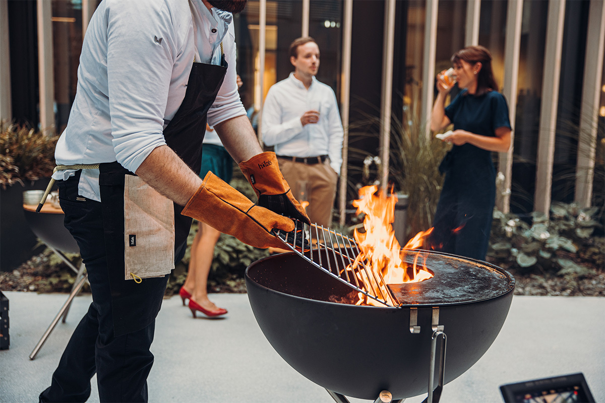 Cette image montre un homme en train de cuisiner sur un grill, avec la Grille BOWL 70.