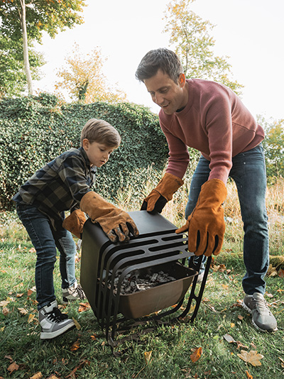 A man and a boy are putting a suitcase, enriched by the presence of the Cube Firebasket, which merges design with utility.