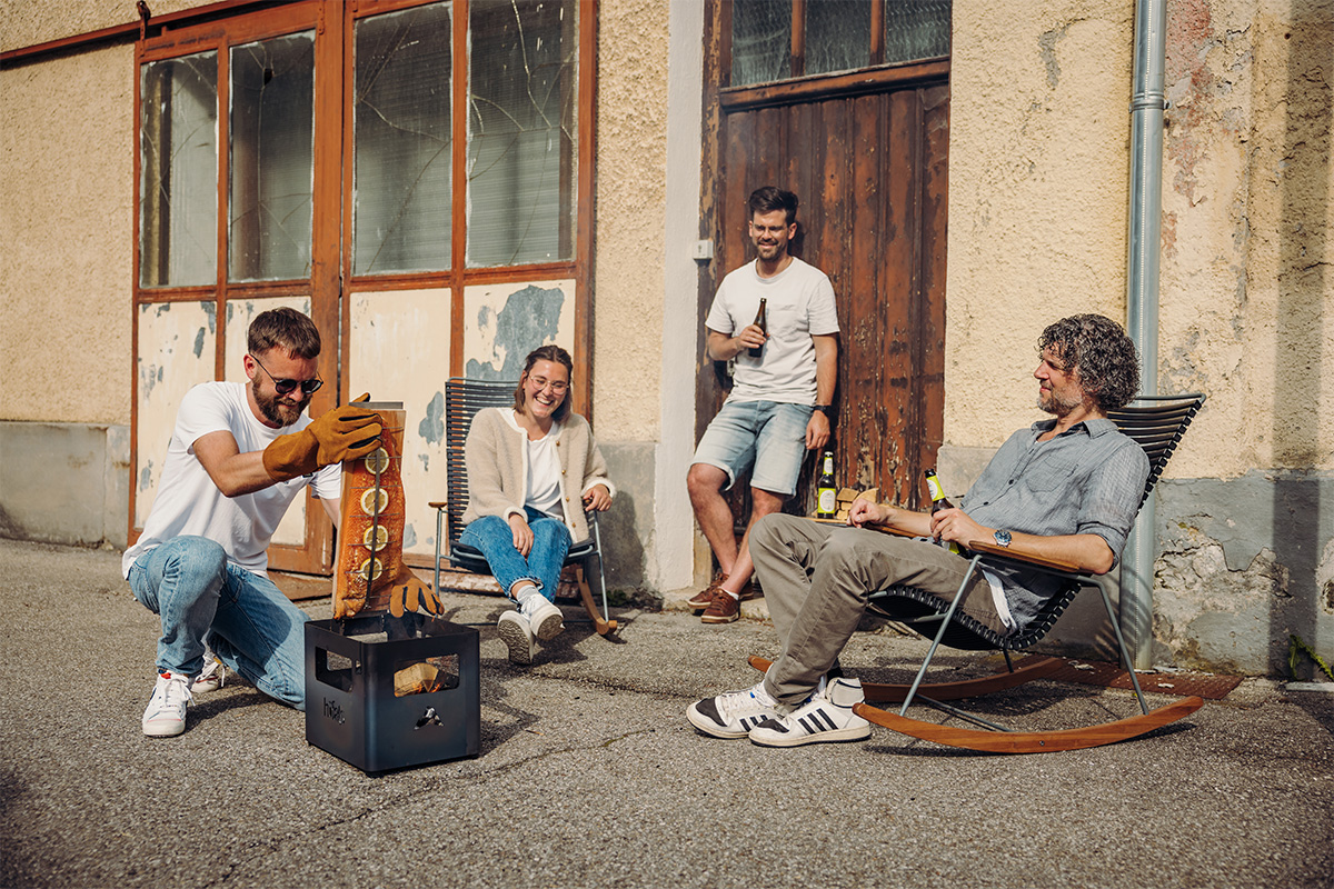 Dargestellt ist eine Gruppe von Menschen, die auf einem Bürgersteig sitzen, mit dem Flame-grilled Lachs-Brett.