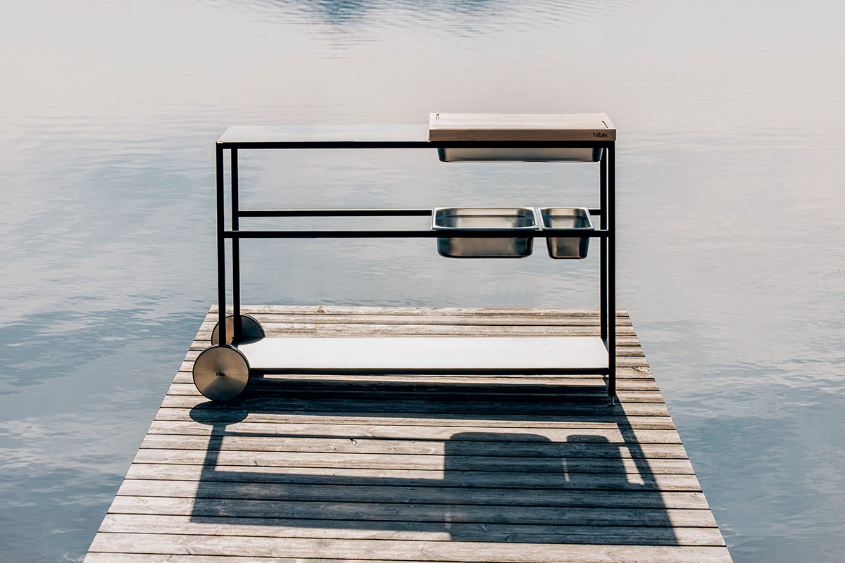 FIRE KITCHEN Cuisine d'extériur Ici est représenté un BOWL sur un cadre métallique sur un quai dans l'eau, avec la cuisine d'extérieur FIRE KITCHEN.