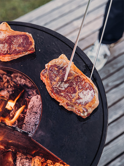 Une image montrant un grill avec de la viande, avec le CUBE Plancha.