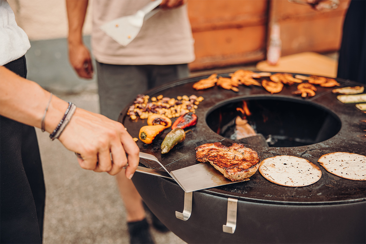 BBQ-Tool-Set Auf dem Bild ist eine Person beim Kochen von Essen auf einem Grill zu sehen.