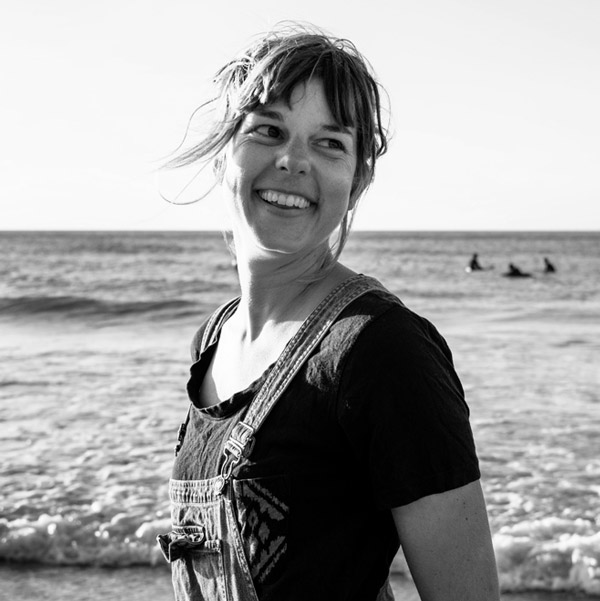 Une femme debout sur la plage avec ses cheveux qui flottent au vent.