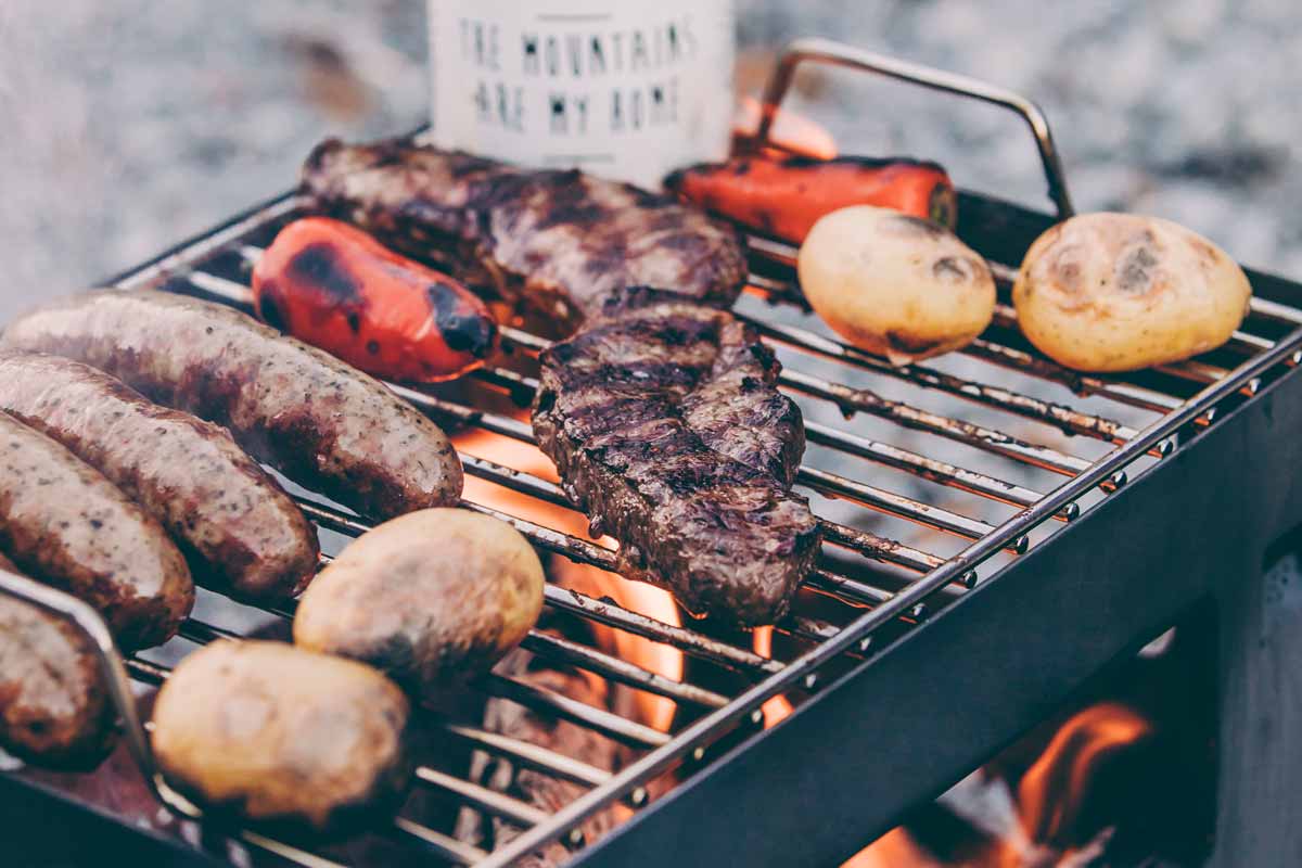 BEER BOX Grid A view of a grill with meat and vegetables on it, with the BEER BOX Grid.