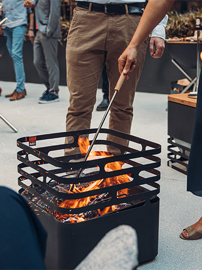 a man and woman standing around a fire pit.