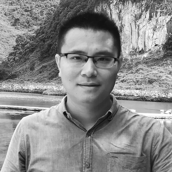 a man in glasses standing on a beach.