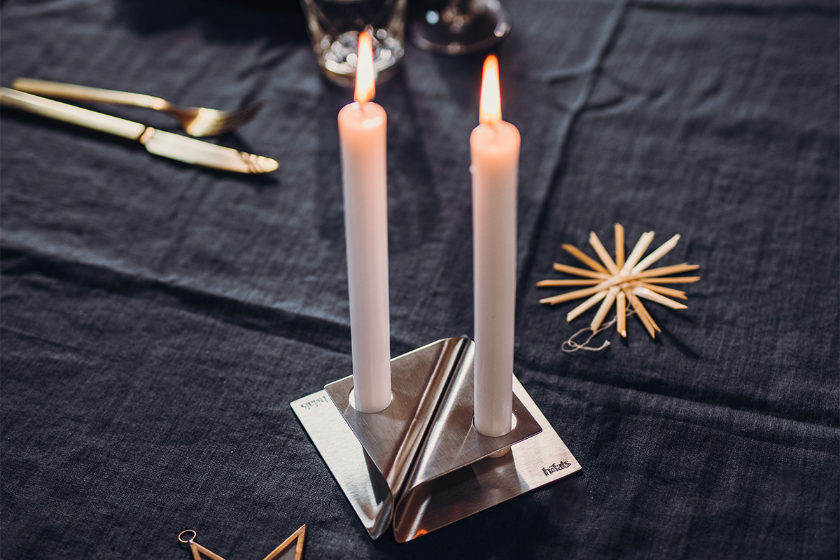 Une image montrant une bougie et une serviette sur une table, avec le porte-bougie SQUARE CANDLE en argent.