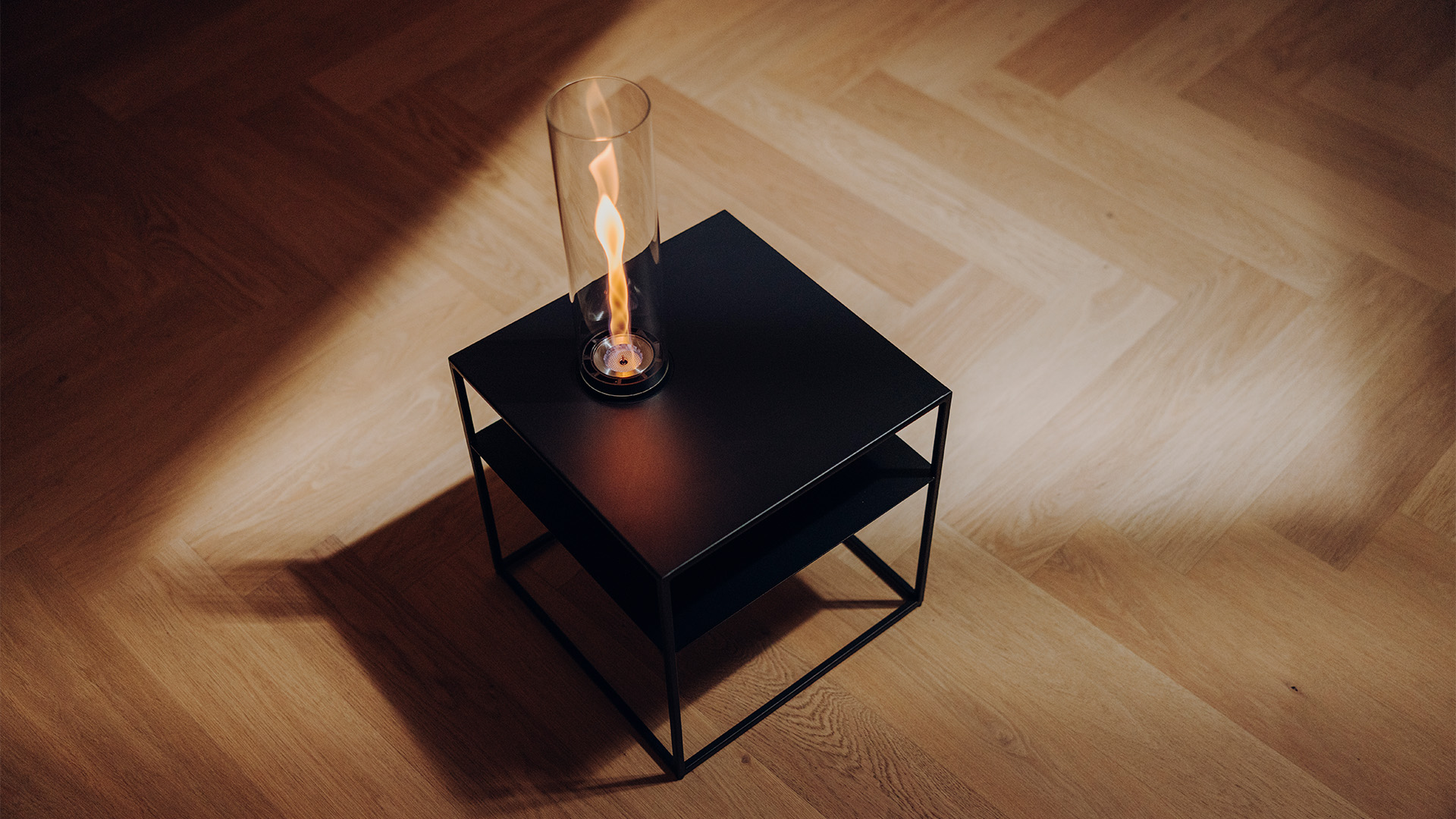 FIRE FRAME mit SPIN air 900 Einbau steht auf einem Parkettboden. Die Flamme brennt.