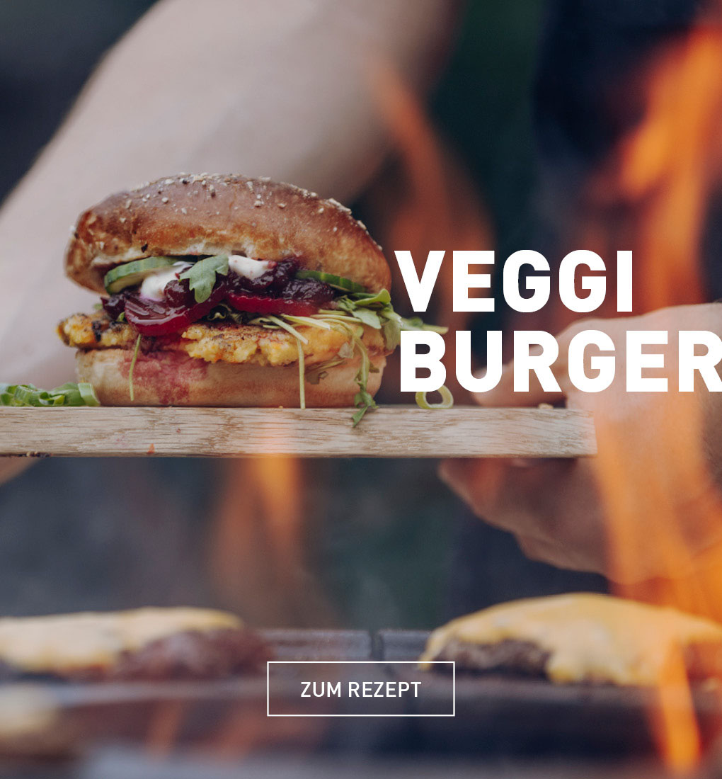 Eine Person hält einen Hamburger auf einem Grill.