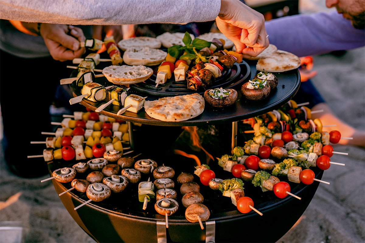 BOWL 57 Anneau Chauffant Cette image montre une personne tenant une assiette de nourriture sur une table, avec le BOWL 57 Warming Ring.