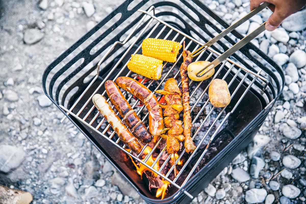 CUBE Grid Experience a person grilling chicken on a grill with the refined touch of the Cube Firebasket black