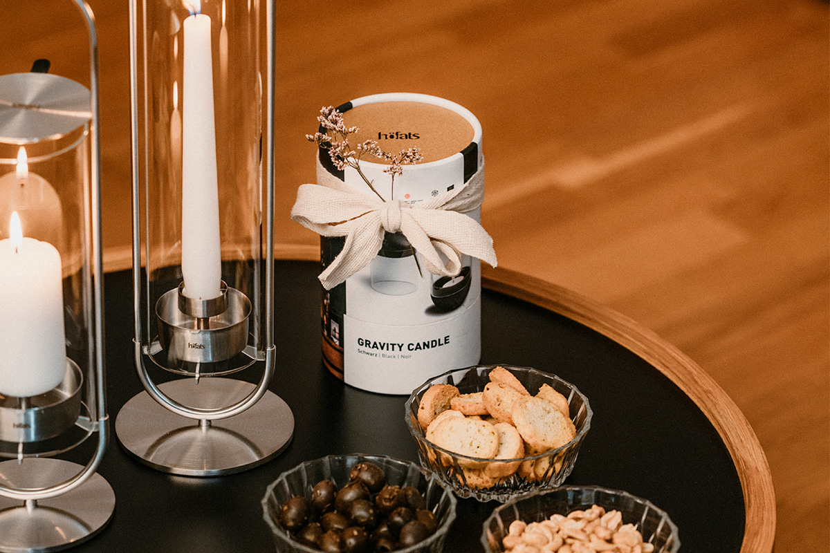 a table with a candle, a bowl of nuts, and a candle holder with the refined touch of the Gravity Candle
