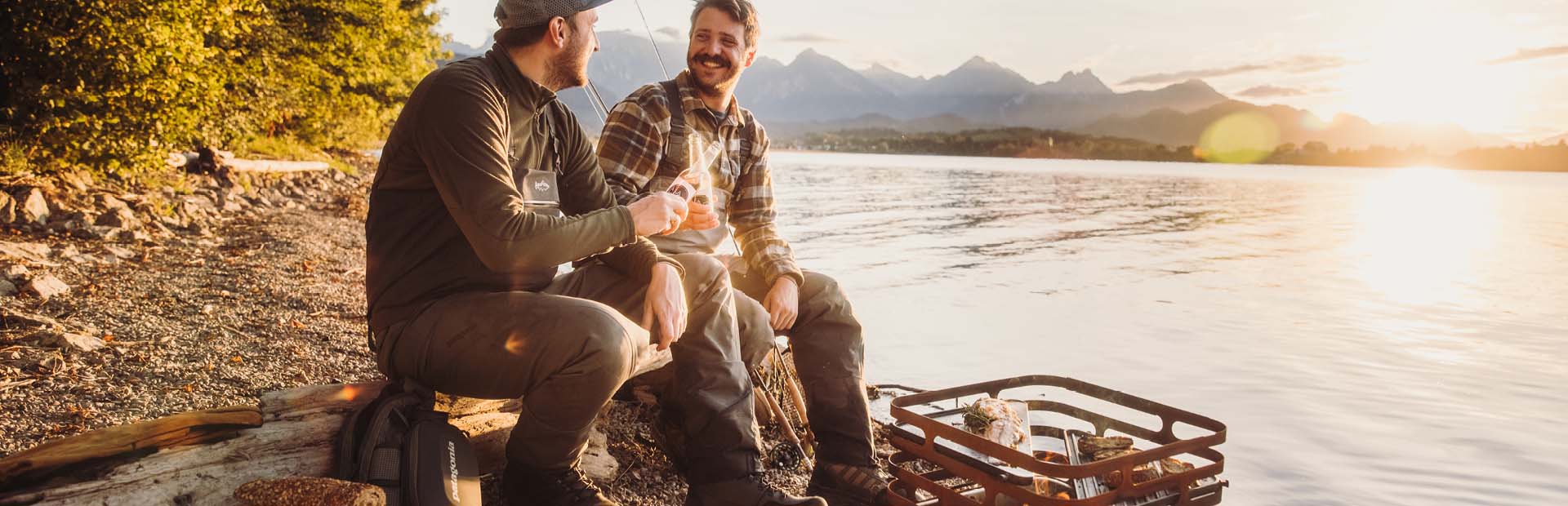 a man and woman sitting on a log by the water