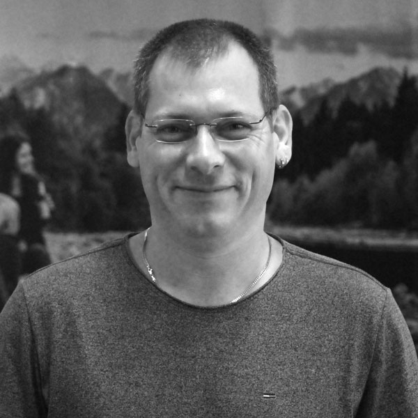 a man in glasses standing in front of a painting.