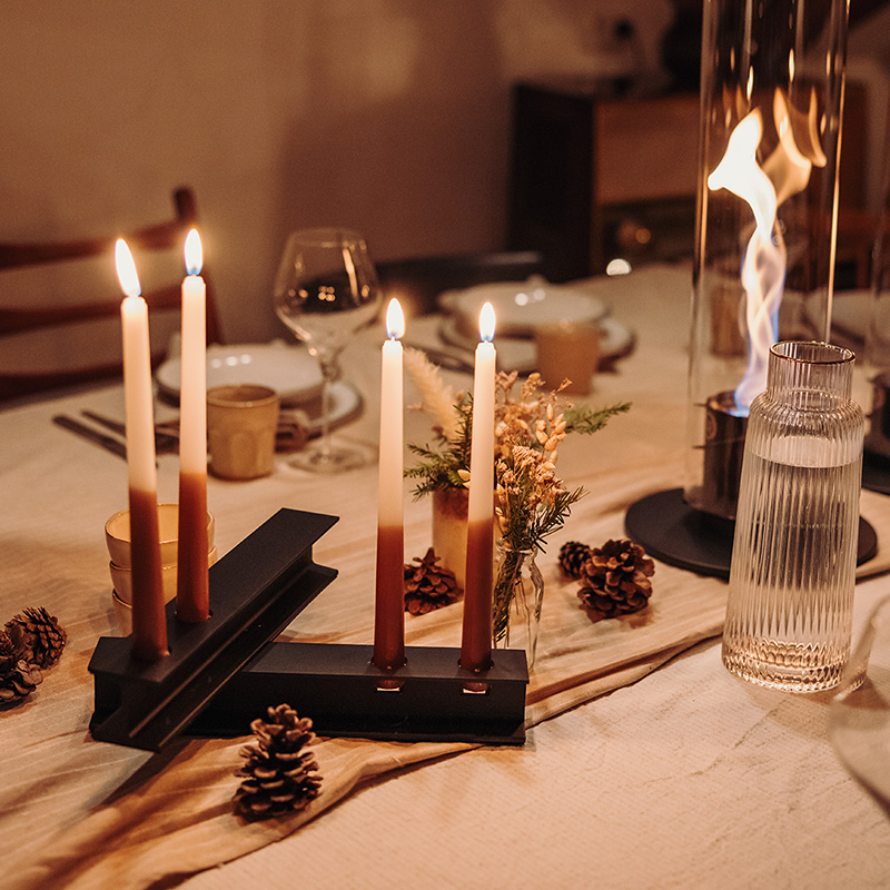 A table with a candle and a candle holder, with the Henry Metal II adding a functional and elegant touch to the scene.