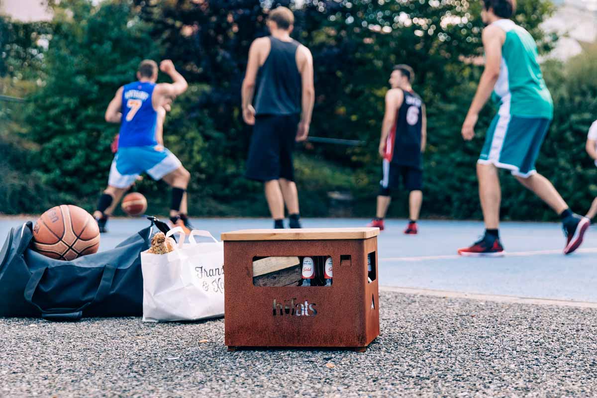 BEER BOX Auflagebrett Eine Darstellung eines Basketballplatzes mit einem Stahlkasten darauf, wobei der Bierkasten als zentrales und zweckmäßiges Element dargestellt wird.