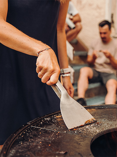 Une vue d'un homme coupant un morceau de viande sur un grill, avec la Plancha CUBE.