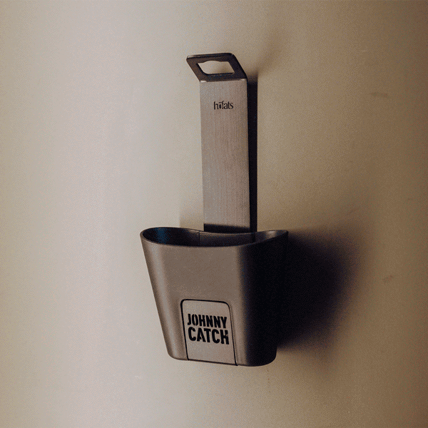 Une image animée montrant le 00842 Johnny Catch Cup Black ouvre-bouteille en action. Un homme ouvre une bouteille de jus d'orange.