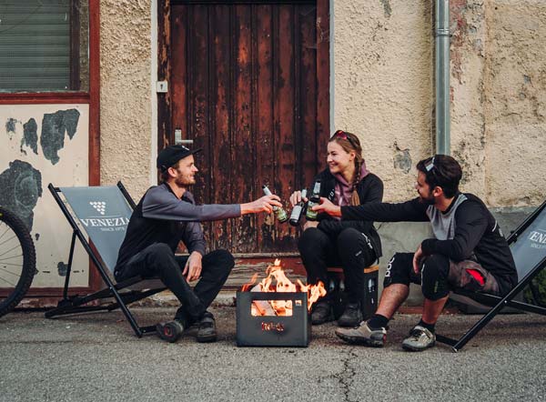 Feuer unterm Sattel Das Foto zeigt drei Personen, die um einen Feuerkorb sitzen, mit dem BEER BOX Feuerkorb.