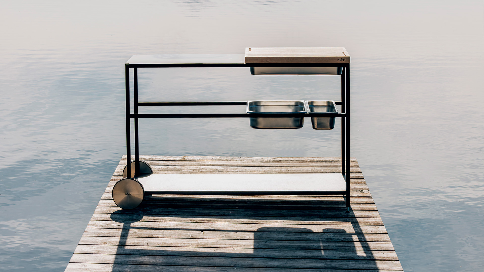 Une image montrant un grill sur un quai dans l'eau, avec la cuisine extérieure FIRE KITCHEN.